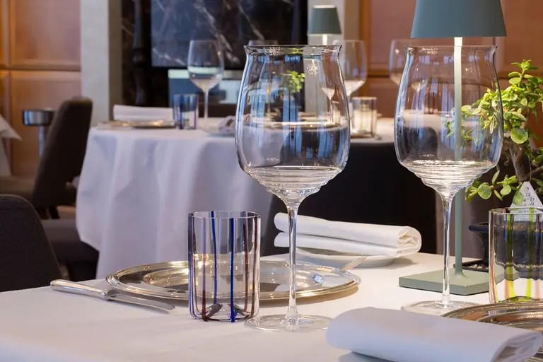 La mise en place: i calici e i bicchieri a righe blu su un tavolo della sala